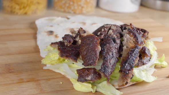 Slow Motion Slider Shot of Adding Finely Sliced Onions to a Doner Kebab in Naan Bread at Home in the