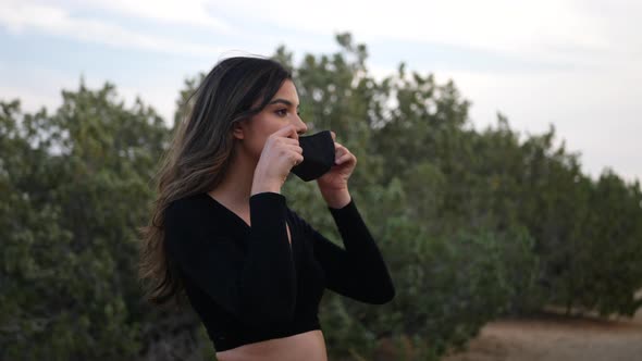 Adult hispanic woman putting on a reusable cloth respiratory face mask to prevent disease from the c