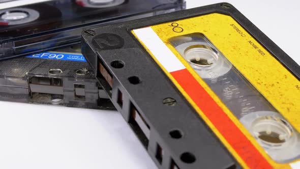 Three Vintage Audio Cassettes Rotate on White Background