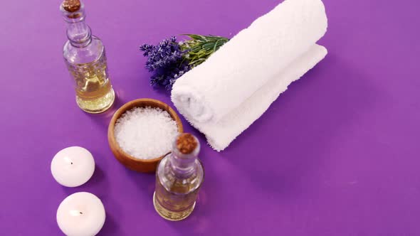 Sea salt in wooden bowl, towel, oil, candle and flowers