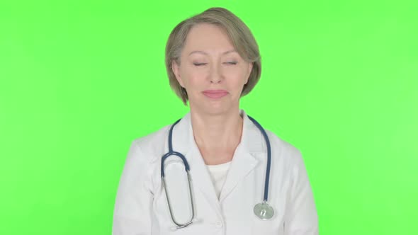 Old Female Doctor Shaking Head in Approval on Green Background