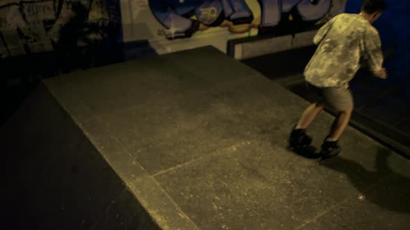 Teenage Riders Training Together at Skatepark with Graffiti Wall in Evening