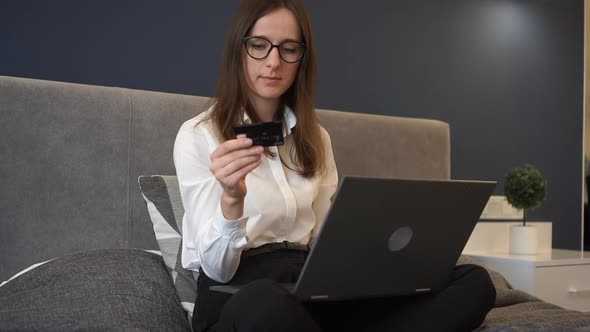 An European Girl Lying on Large Bed with Her Laptop Having Online Shopping Keying in the Card