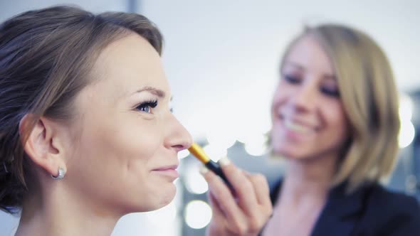 Makeup Artist Applying Cosmetic Tonal Foundation and Powder on the Face Using Brush