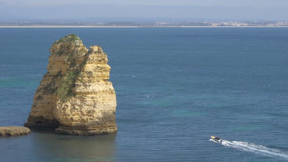 Boat sailing by a cliff in the middle of a sea