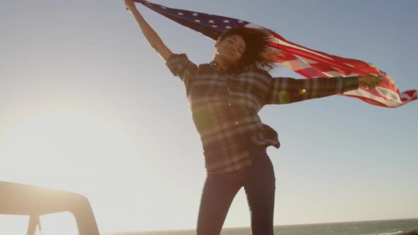 Woman waving american flag on pickup truck at beach 4k