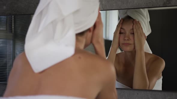 Caucasian woman looking in mirror after shower in hotel