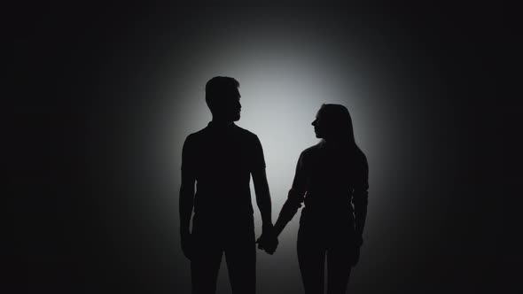 A Silhouette of a Man Stands Next To a Silhouette of a Woman and Takes Her Hand