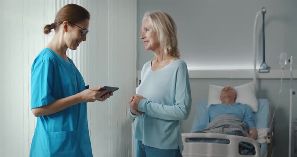 Smiling Aged Woman Talking To Doctor Discussing Sick Husband Recovery