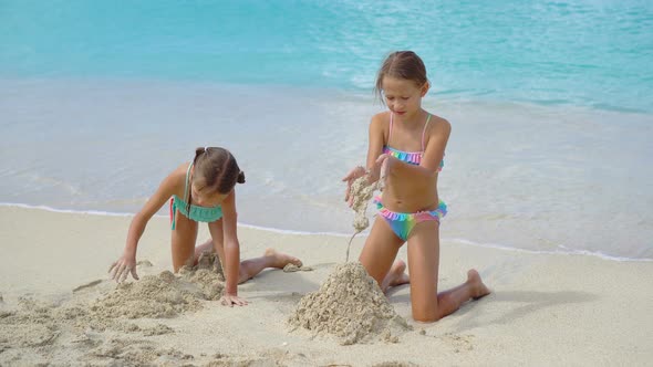 Two Little Happy Girls Have a Lot of Fun at Tropical Beach Playing Together at Shallow Water. Kids