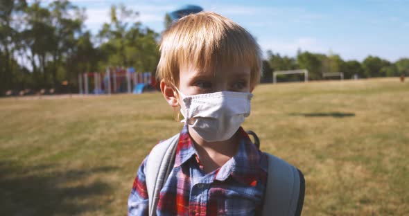 Little boy in a school field wearing a face mask.