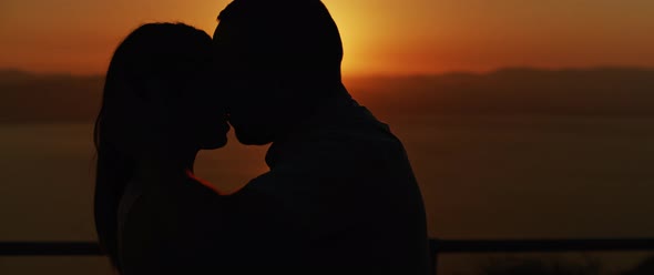 Close up of a young couple kissing at sunset, spending a romantic evening together. Slow motion