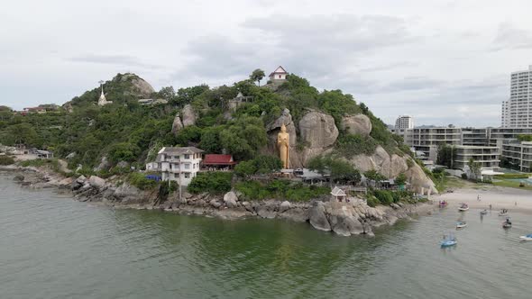 Famous Golden Buddha Statue on Rock Shore in Hua Hin, Takiap Beach. Orbiting shot