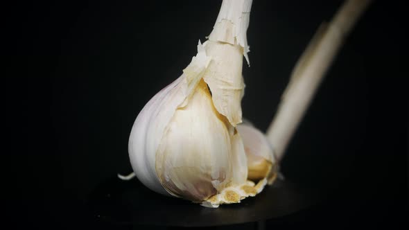 Cloves Of Fresh Garlic Rotating In Black Background In The Studio - close up