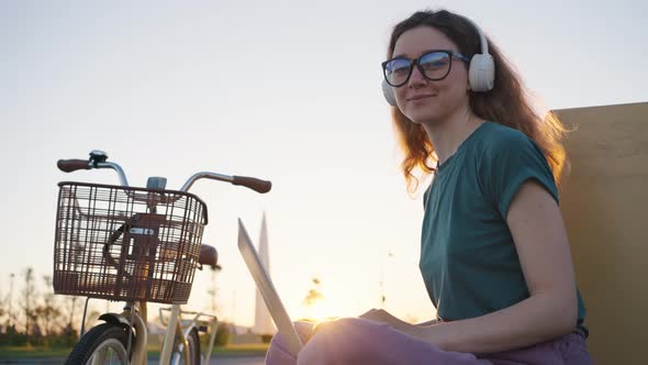 Young Woman in White Headphones Enjoys Working Freelancer