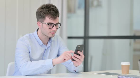 Attractive Young Man Using Smartphone in Office