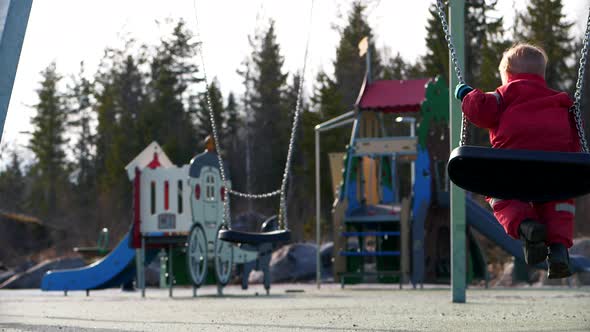 Kids in swings at empty outdoor playground in Europe, quarantine concept