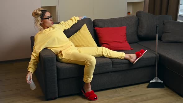 Young Woman in Yellow Hoodie Is Resting After Cleaning