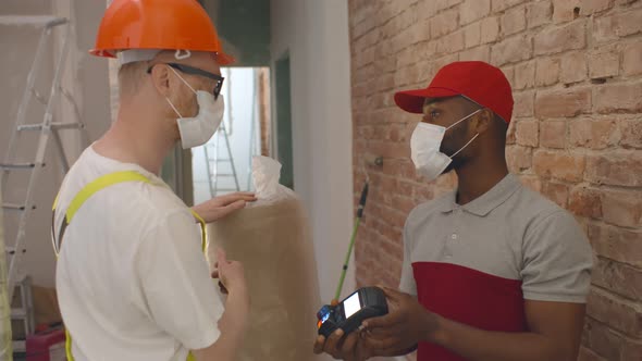 Foreman Paying with Credit Card for Delivery To Courier at Construction Site