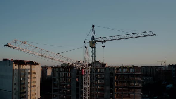 Aerial Drone View of Construction Cranes in Sunset Light. Construction Site Building in City