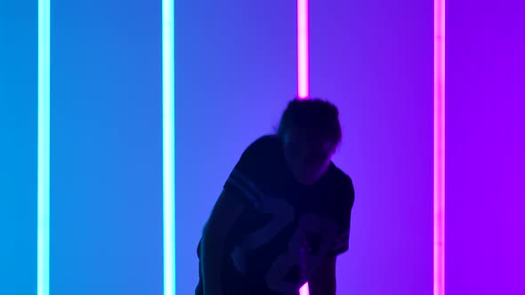 Young Woman Dancing Hip Hop Street Dance in Studio with Neon Lighting Tube on Blue Purple Background