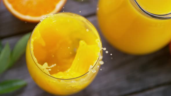 Super Slow Motion Shot of Ice Falling to Fresh Orange Juice in a Glass at 1000Fps