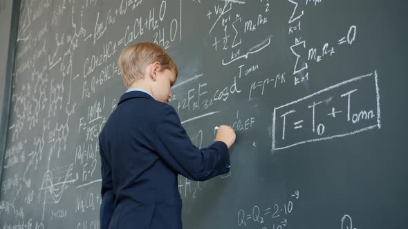 Young Student Stydying at School Writing on Chalkboard Busy with Science