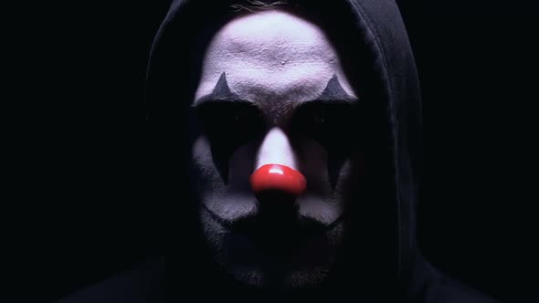 Evil Clown Smiling to Camera Against Dark Background, Dangerous Maniac in Mask