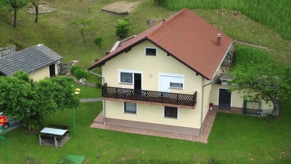 Family house with yellow facade in middle of green nature. 4k aerial drone view.
