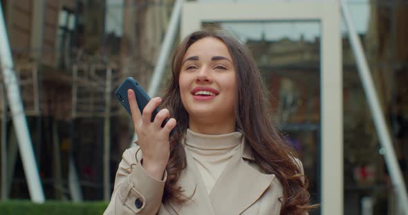 Woman Using a Smart Phone Voice Recognition Function Online Near Big Modern Office Building, Talking