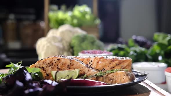Juicy salmon steaks on plate decorated with herbs and sauce.