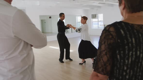 mixed race male dance teacher taking a ballroom dancing class at a dance studio