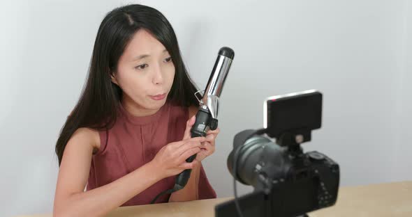 Woman making hair in front of the digital camera to take vlog on social media 