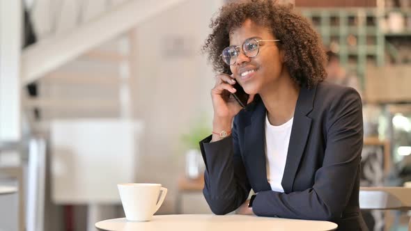 Cheerful African Businesswoman Talking on Smartphone at Cafe