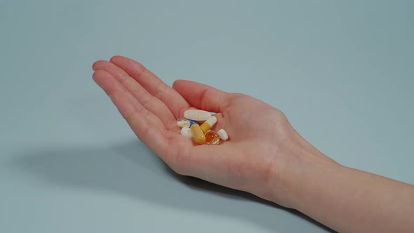Handful of tablets and capsules of various shapes. Blue background