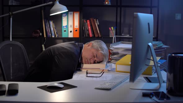 Businessman falling asleep at his work desk.