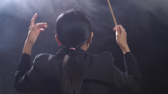 Back View Asian Conductor Woman Holding A Baton And Showing Gesture Quickly In The Black Studio