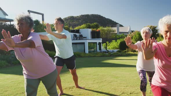 Senior diverse people exercising in garden on sunny day at retirement home