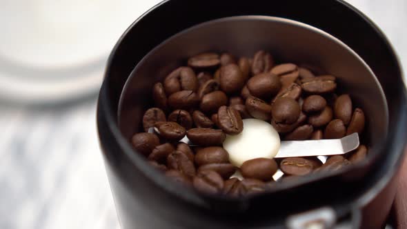 Closeup coffee beans in a stainless coffee grinder with shiny blades