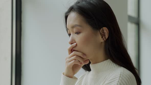 Asian Woman Looked Out the Window She is Lonely and She Touches Her Face with Her Hands