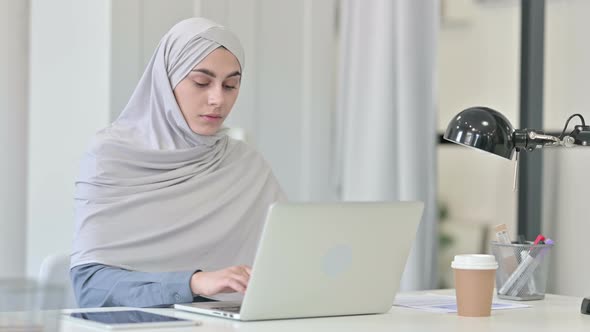 Young Arab Woman Thinking While Using Laptop in Office