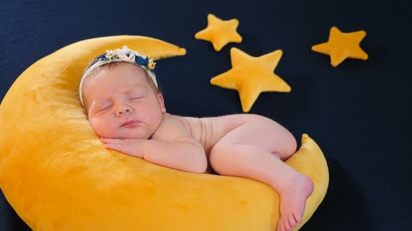 Little Infant As Model at Photo Shoot Sleeping and Posing on Yellow Soft Toy in Moon Shape and Stars