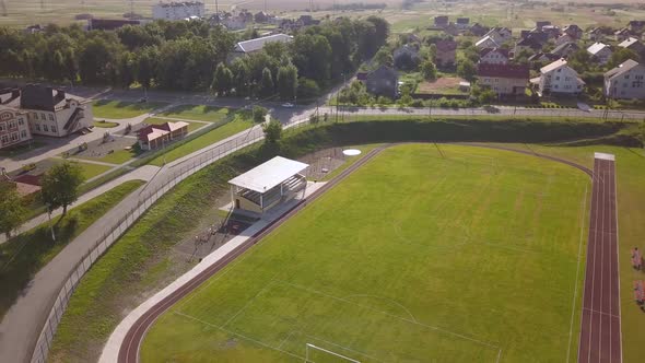 Aerial View of a Football Field on a Stadium Covered with Green Grass in Rural Town Area