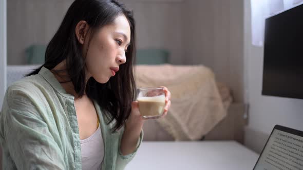 Asian writer with laptop and coffee at home