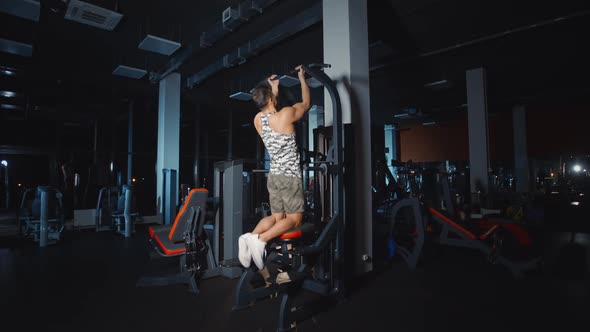 Bodybuilder Doing Pull Ups Training Hands on Weights Lifting Exercise Machine Work Out in Gym