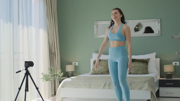 Fit brunette woman in blue sportswear making video for blog morning workout with exercises at home