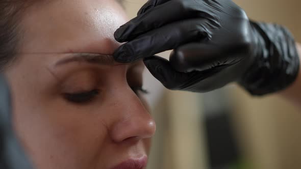 Closeup Shaping Eyebrows for Permanent Makeup in Beauty Salon