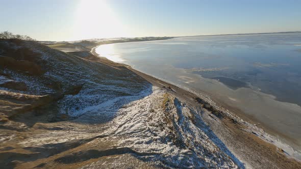 FPV Aerial Shot Going Downhill Along Rough Terrain and Bright Sunlight