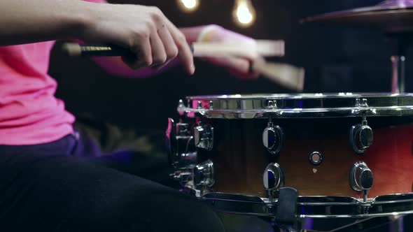 The drummer plays the snare drum with sticks close up.