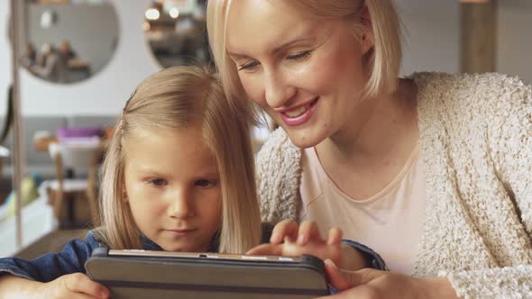 Little Girl Flips on Tablet at the Cafe